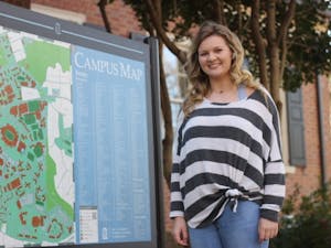 Kamryn Sain, a legacy student, smiles by a UNC campus map on Wednesday, Feb. 13, 2019. Both of Sain's parents attended UNC.