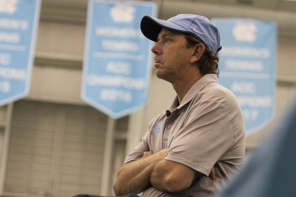 <p>UNC women's tennis Head Coach Brian Kalbas crosses his arms on the sidelines as he observes the team play against Vanderbilt on Sunday, Feb. 2, 2020. UNC won 7-0.</p>