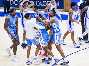 First-year guard Caleb Love (2) is embraced by his teammates following UNC's 91-87 victory over Duke at Cameron Indoor Stadium, Feb 6, 2021. Photo courtesy of Natalie Ledonne.