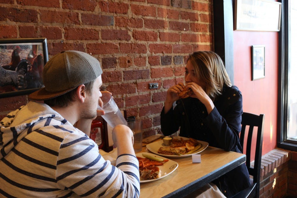UNC junior Taylor Halterman and Chapel Hill resident Jake Lewis enjoy a meal at Roots, located on Franklin St., on Friday, Jan. 25, 2019. The restaurant is closing on Feb. 17, 2019 and plans to reopen in Durham. One of the owners, Gabriel Ordonez, wants to promote the new location by giving coupons to customers that visit the Franklin location before it closes.