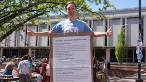 Graduate student Jimmy Doegerl wears a cardboard list of students' climate demands at Climate Action Day in the pit on Tuesday, April 13, 2023.