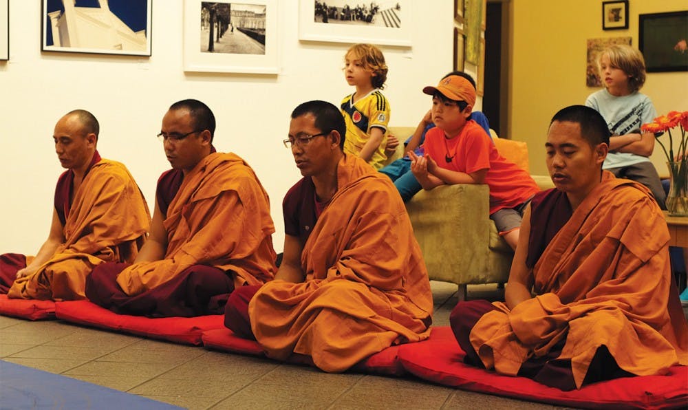 A group of Tibetan monks pray around their sand mandala in The ArtsCenter in Carrboro on Monday. The mandala will be complete Friday.