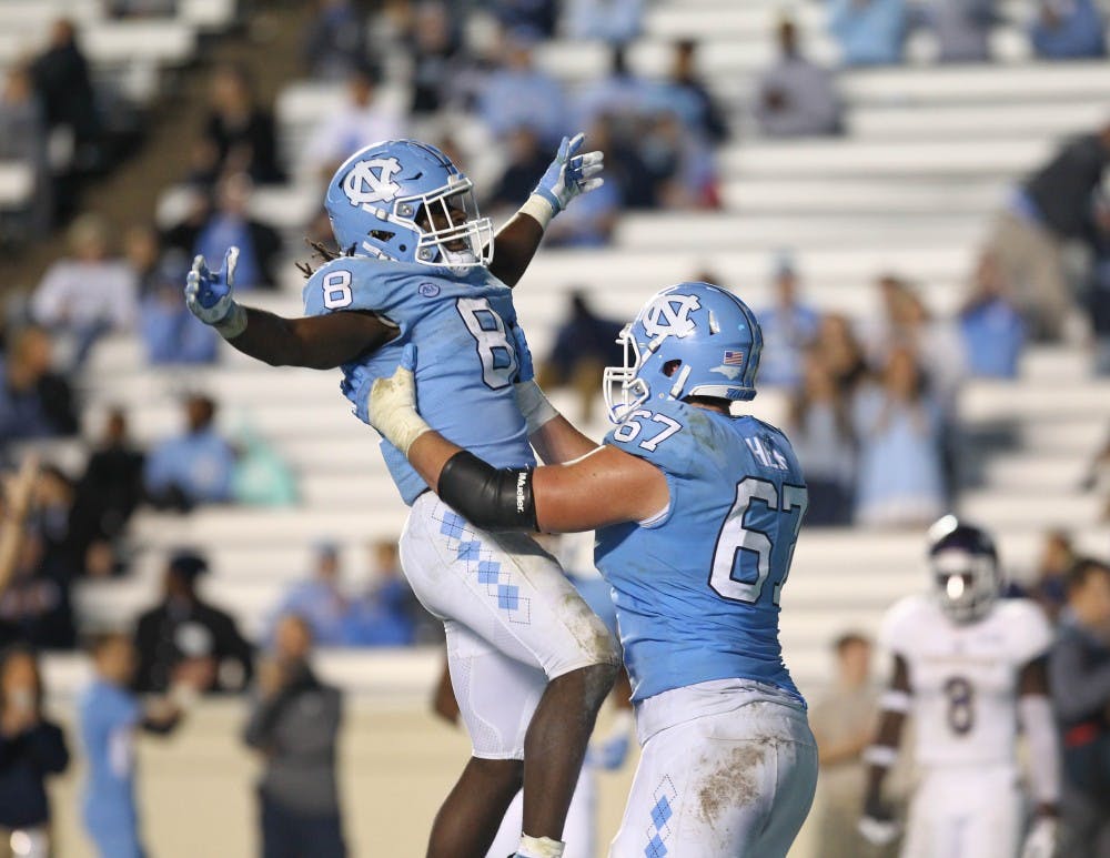 Running back Michael Carter (8) celebrates with offensive lineman Charlie Heck (67) after scoring a touchdown against Western Carolina on Nov. 18, 2017 at Kenan Stadium.