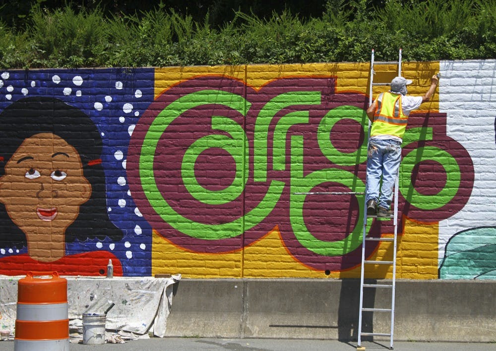 UNC graduate Michael Brown paints a mural for the City of Carrboro off of Jones Ferry Road on Tuesday afternoon.