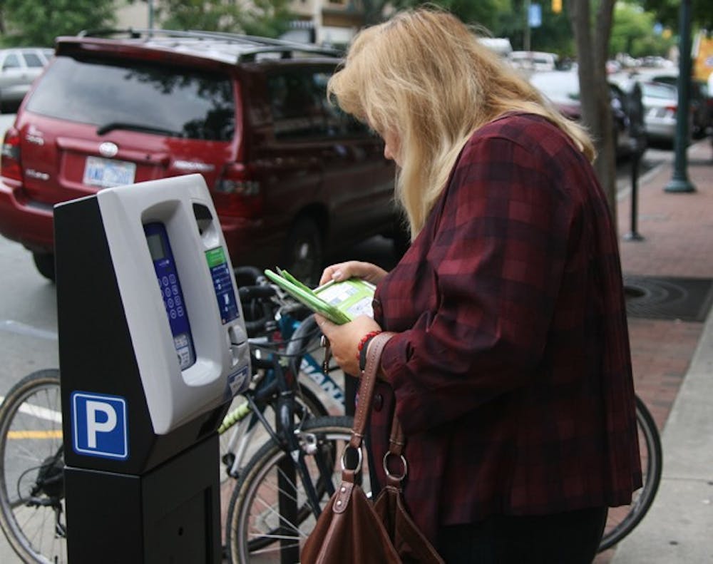 Sylvia Torrelli uses a new parking meter that has cropped up along Franklin Street. The new meters oversee multiple spaces at a time.