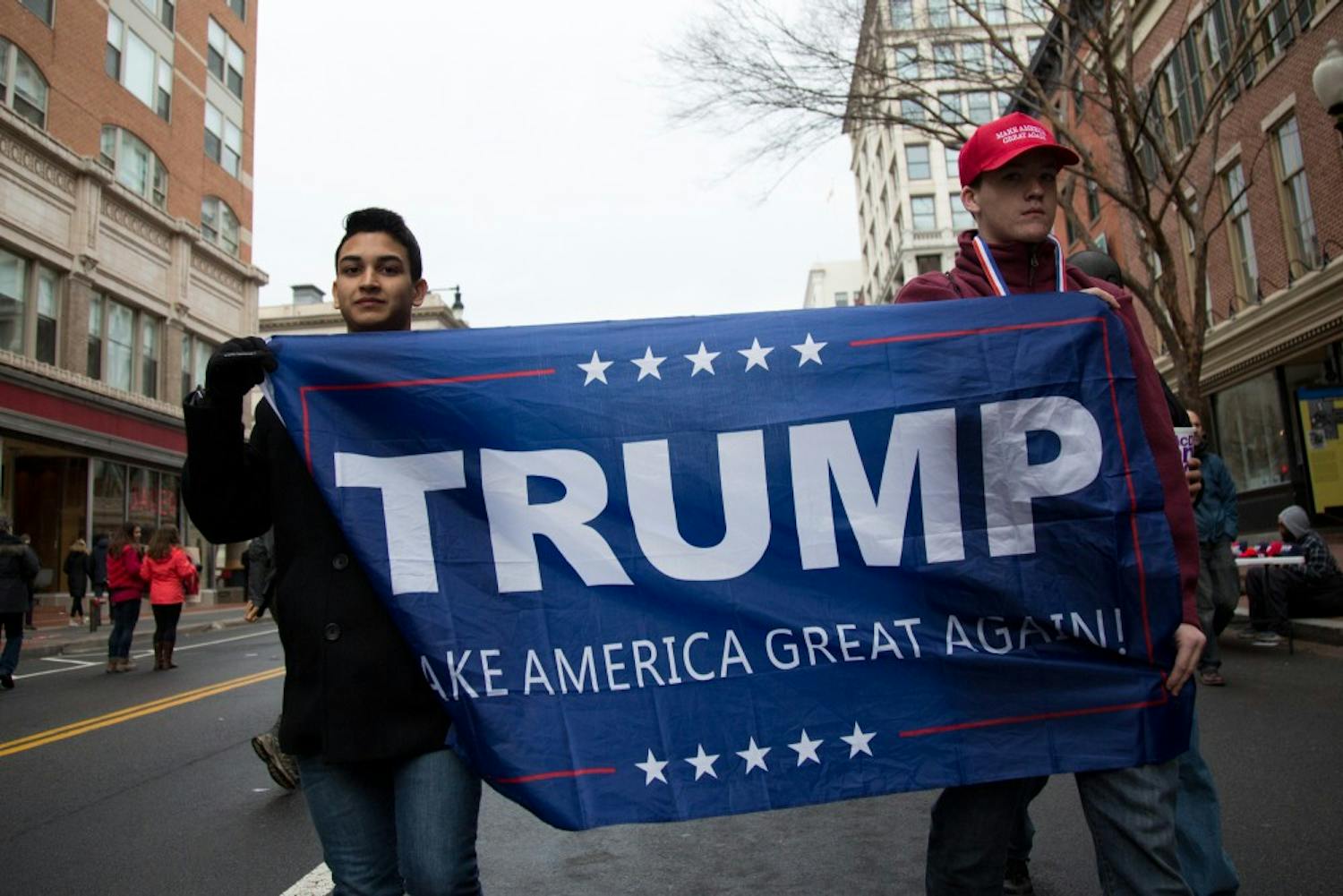 Two Trump supporters carry a banner embroidered with his name through the streets of Washinton on Inauguration Day.