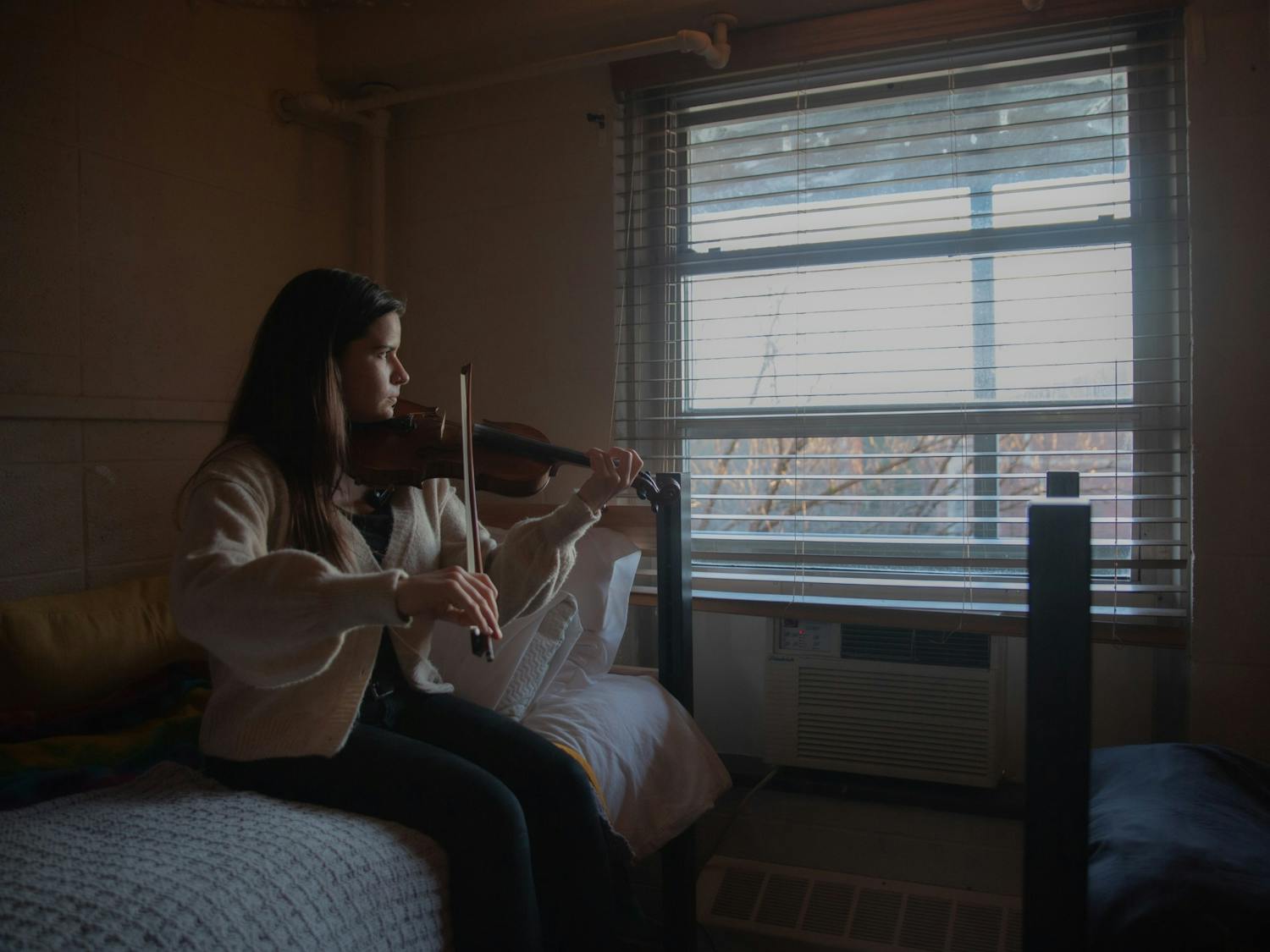 DTH Photo Illustration. A student plays the violin in her room at on Thursday, Jan. 28, 2021. As local musicians are impacted by the pandemic, Tracks Music Library is offering an opportunity for artists to share their work with the community.