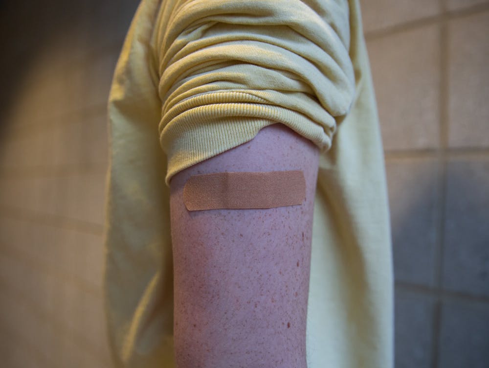 DTH Photo Illustration. A bandage sits on a student's arm. As the COVID-19 vaccine becomes available, students are sharing their experiences and reasons for getting the shot.