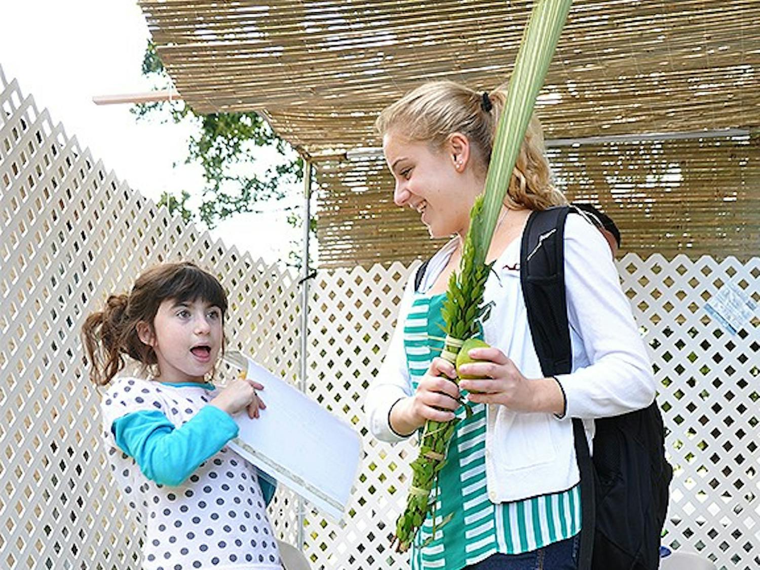 Chaya Bluming (left) and Adi Blanc (right) recite a Jewish blessing in the traveling sukkah.