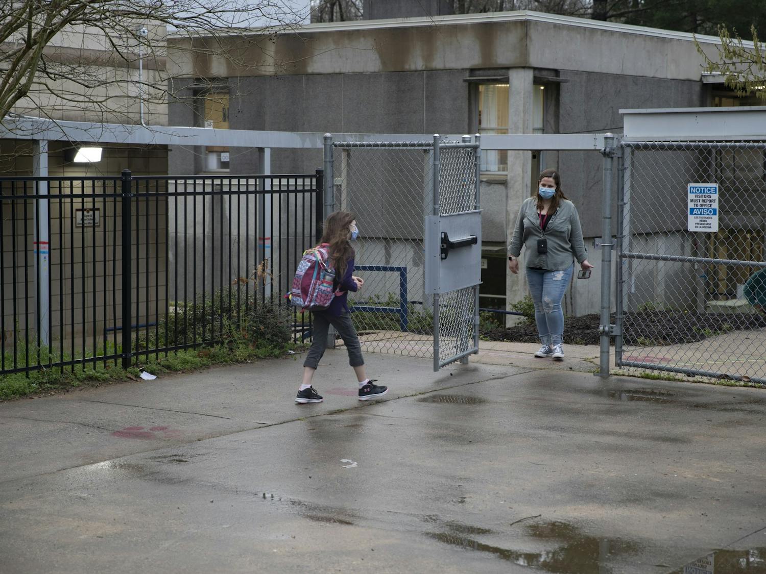 A student of Frank Porter Graham Elementary school walks from carpool toward the school early in the morning on March 26, 2021. CHCCS have recently reopened in-person instruction, although many children are still learning virtually.