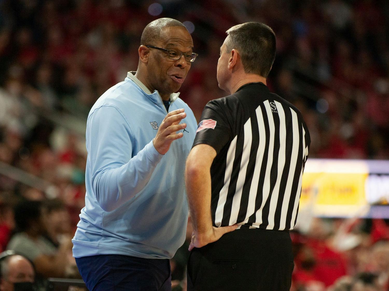 UNC head coach Hubert Davis speaks with a referee at the men's basketball game against N.C. State on Feb. 19, 2023, at PNC Arena. N.C. State won 77-69.&nbsp;