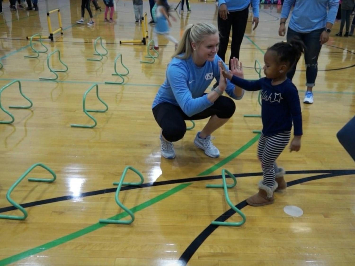 UNC track and field athlete Emily Godwin high fives a participant during National Girls and Women in Sports Day, hosted at UNC.