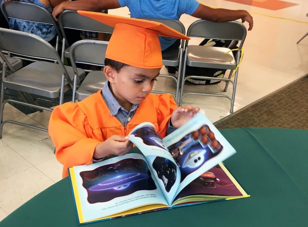 A member of the inaugural class of Book Babies turns pages in a book during the Book Babies class of 2018 graduation ceremony. Photo courtesy of Ginger Young.