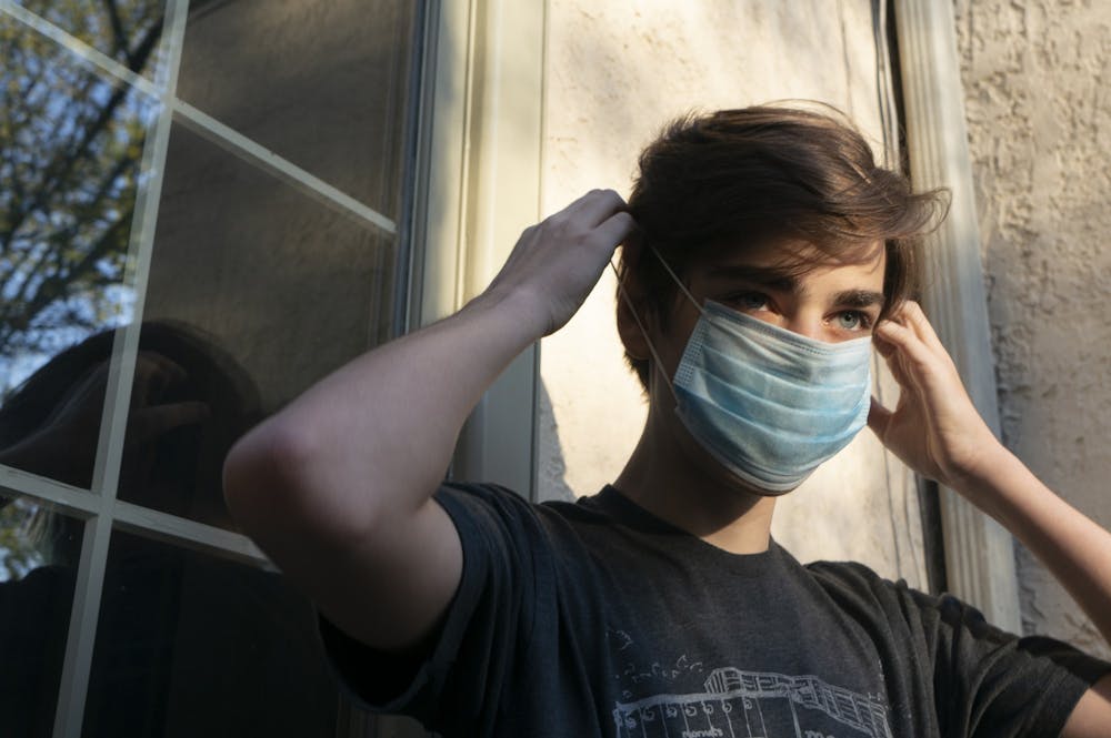 A student puts on a mask before leaving his house on Wednesday, May 20, 2020.
