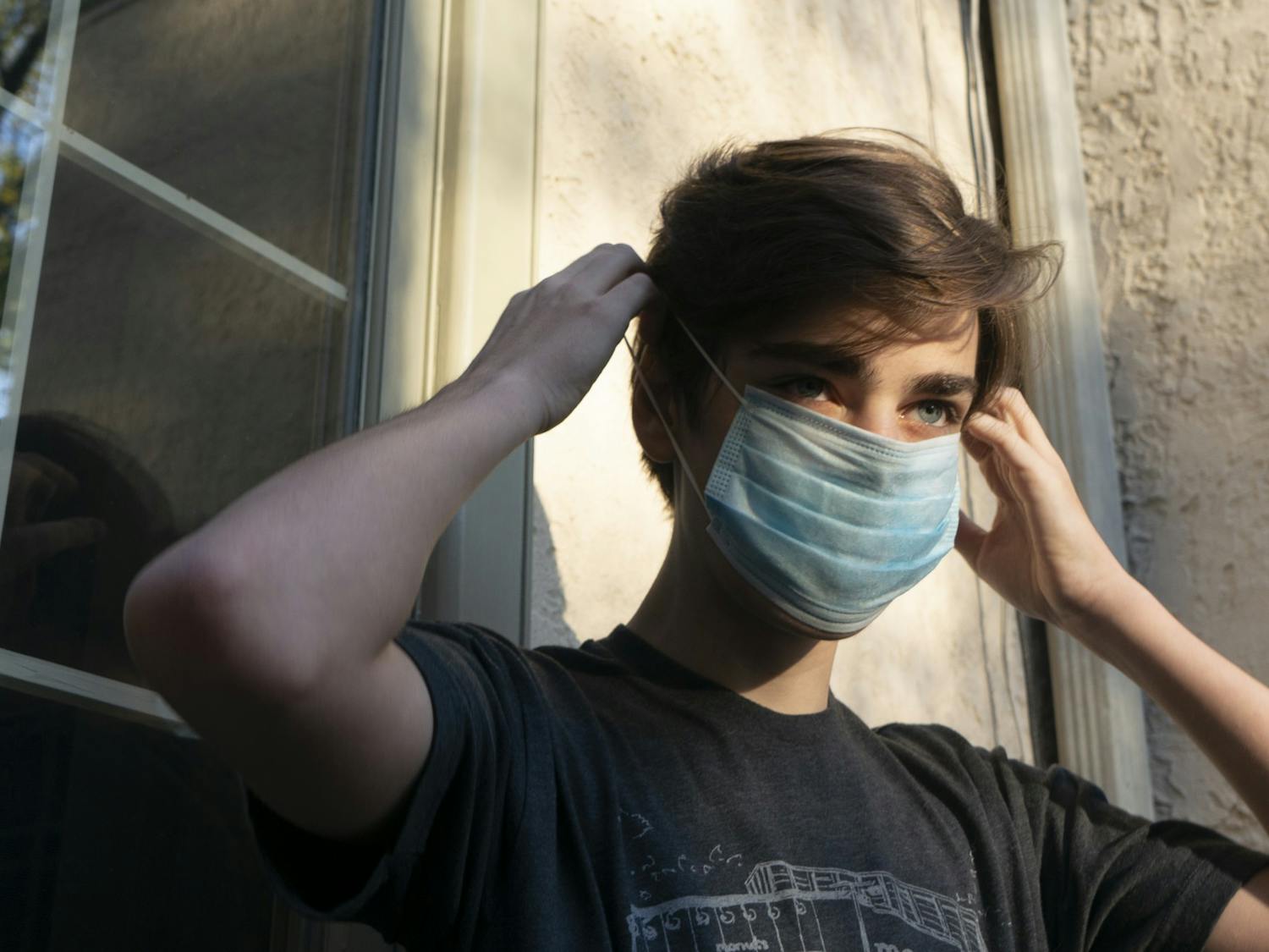 A student puts on a mask before leaving his house on Wednesday, May 20, 2020.