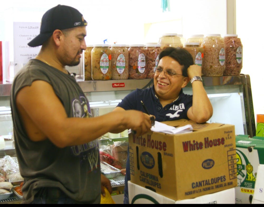David Hernandez delivers a package and talks with Raymundo Arenas, employee of La Potosina, a Latino market on Rosemary Street.