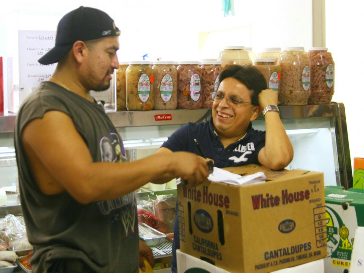 David Hernandez delivers a package and talks with Raymundo Arenas, employee of La Potosina, a Latino market on Rosemary Street.
