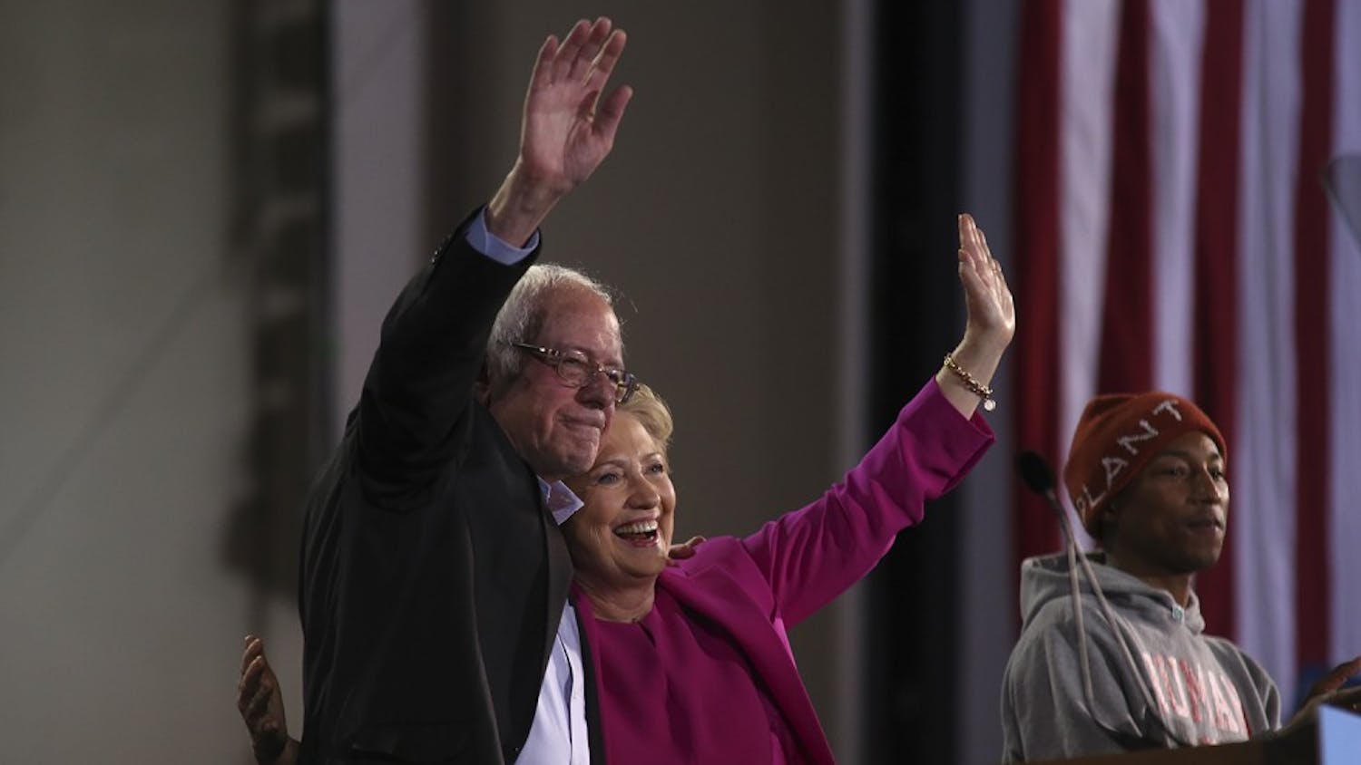 Bernie Sanders (left) and Hillary Clinton wave to the crowd after Pharell Williams’ (right) plea for women's rights.