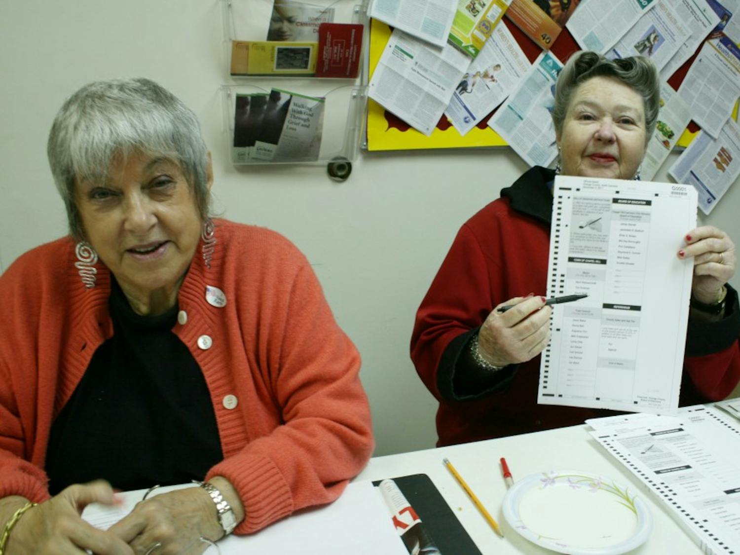left to right: Iris Schwintzer, Shirley Ray, Ernie Quade. Judges for the E Franklin Street Precinct assist morning voters. Deborah Finn, of 214 Hillsborough St., votes with her husband and dog. (purple jacket). At larger elections, Mrs. Finn is also a judge for the E Franklin Street Precinct