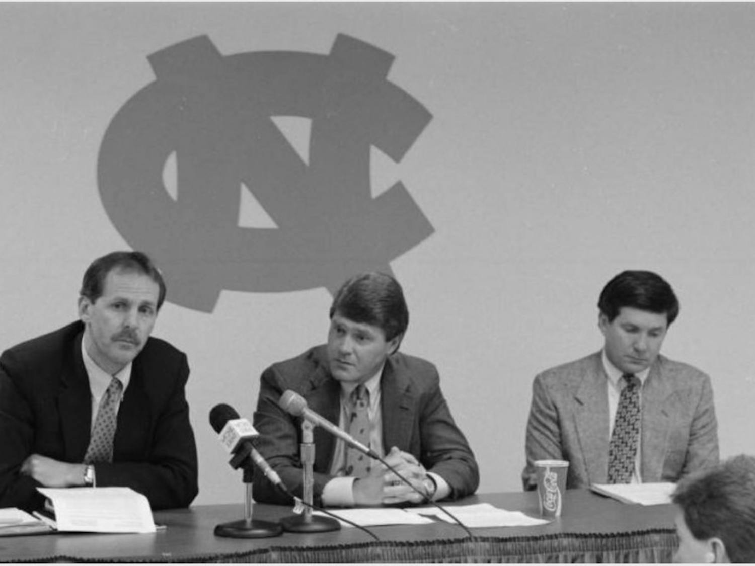 Press Conference, WCHL 1360. (Left to right): Unidentified man, UNC Athletic Director John Swofford, UNC Head Football Coach Mack Brown. In the Hugh Morton Photographs and Films #P0081, copyright, 1988-1994, North Carolina Collection, University of North Carolina at Chapel Hill Library.