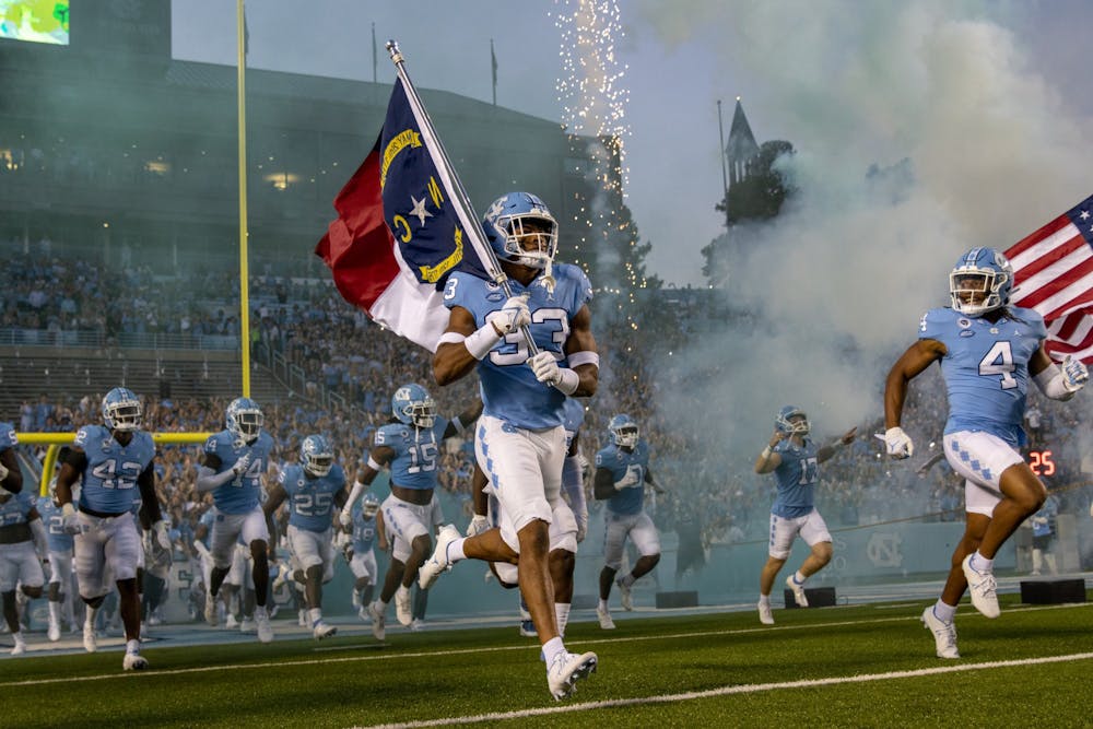 <p>UNC sophomore linebacker Cedric Gray (33) carries in the North Carolina flag before the Tar Heels' home matchup in Kenan Stadium on Saturday, Sept. 11, 2021 against the Georgia State Panthers.</p>