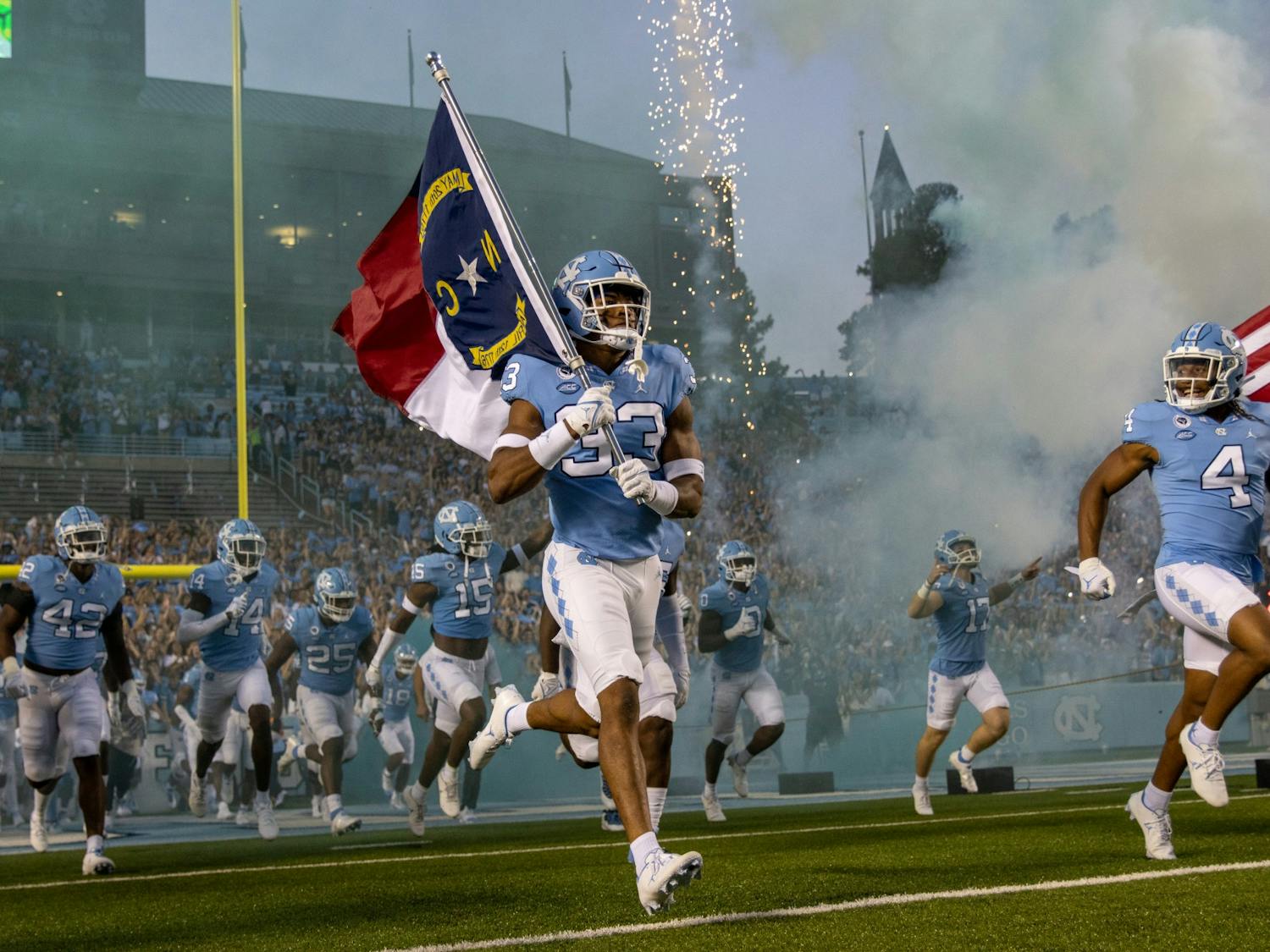 UNC sophomore linebacker Cedric Gray (33) carries in the North Carolina flag before the Tar Heels' home matchup in Kenan Stadium on Saturday, Sept. 11, 2021 against the Georgia State Panthers.