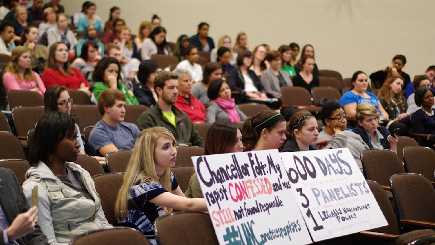 Junior Landi Gambill holds a sign addressing Carol Folt in the screening of the documentary "The Hunting Ground" in the Carroll Hall auditorium on Thursday. 