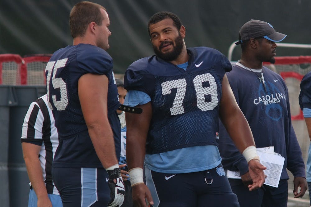 North Carolina senior offensive guard Landon Turner (78) talks with teammate Bentley Spain (75) during an afternoon practice.