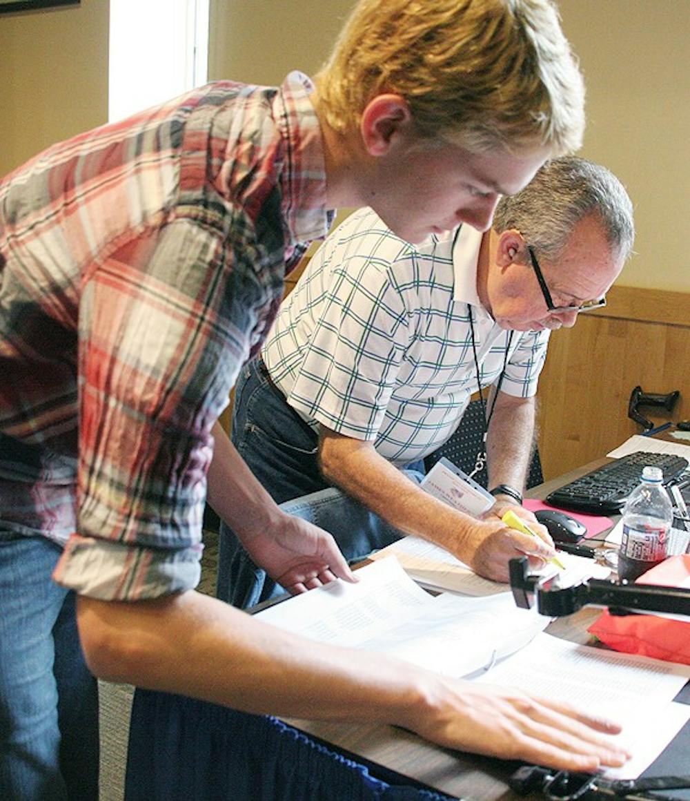 Brian Beaman, a sophomore Psychology/Chemistry double major (left) registers to vote with James Weathers, the Chief Judge of early voting. 