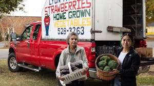 Rose Lyon, co-owner of Lyon Farms, and Kim Trejo, farmer at Lyon Farms, stand with some of their produce at the Carrboro Farmers Market on Wednesday, Oct. 26, 2022.