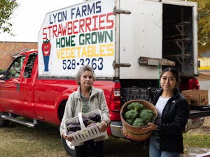 Rose Lyon, co-owner of Lyon Farms, and Kim Trejo, farmer at Lyon Farms, stand with some of their produce at the Carrboro Farmers Market on Wednesday, Oct. 26, 2022.