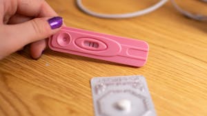 DTH Photo Illustration. A student looks at a positive pregnancy test and a pill. 
