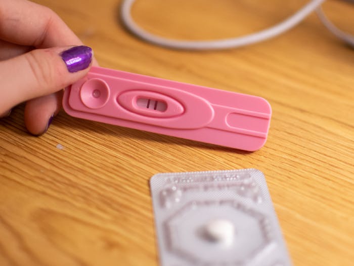DTH Photo Illustration. A student looks at a positive pregnancy test and a pill. 