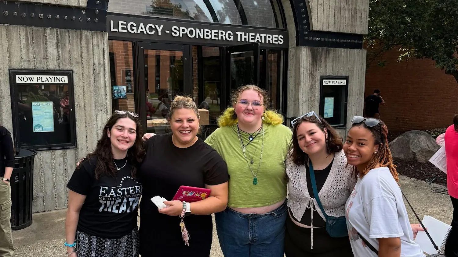 Five people stand side-by-side to pose for a photo outside of Judy Sturgis Hill Building.
