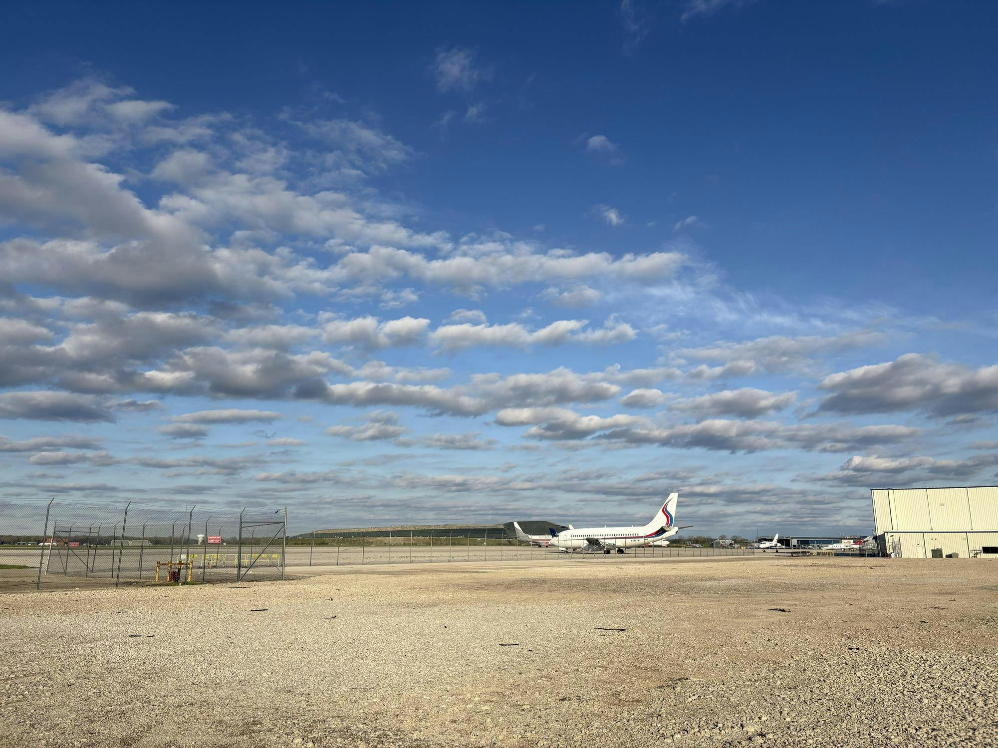 An airplane sits on the ground with a blue sky in the background.