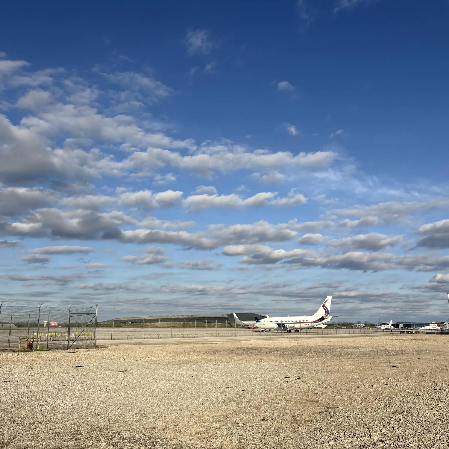 An airplane sits on the ground with a blue sky in the background.