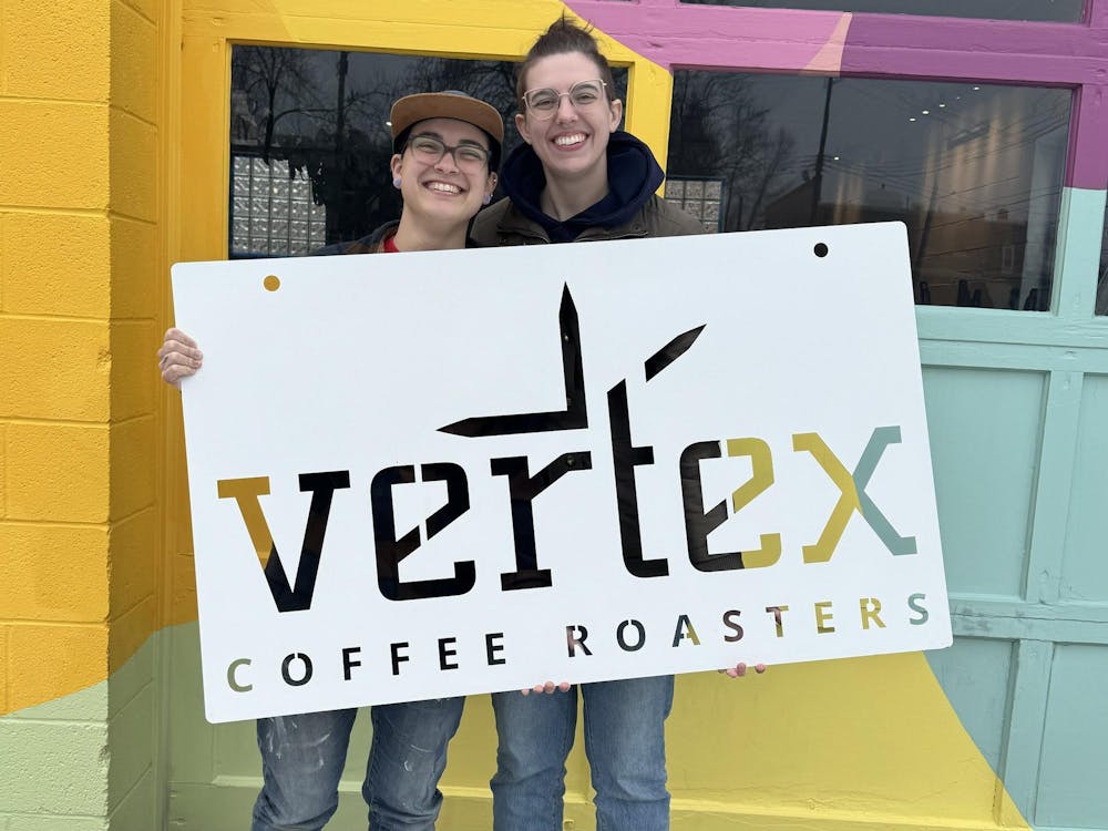 Kara Sato and wife Mackenzie Sato with a sign of their coffee shop, Vertex Coffee Roasters