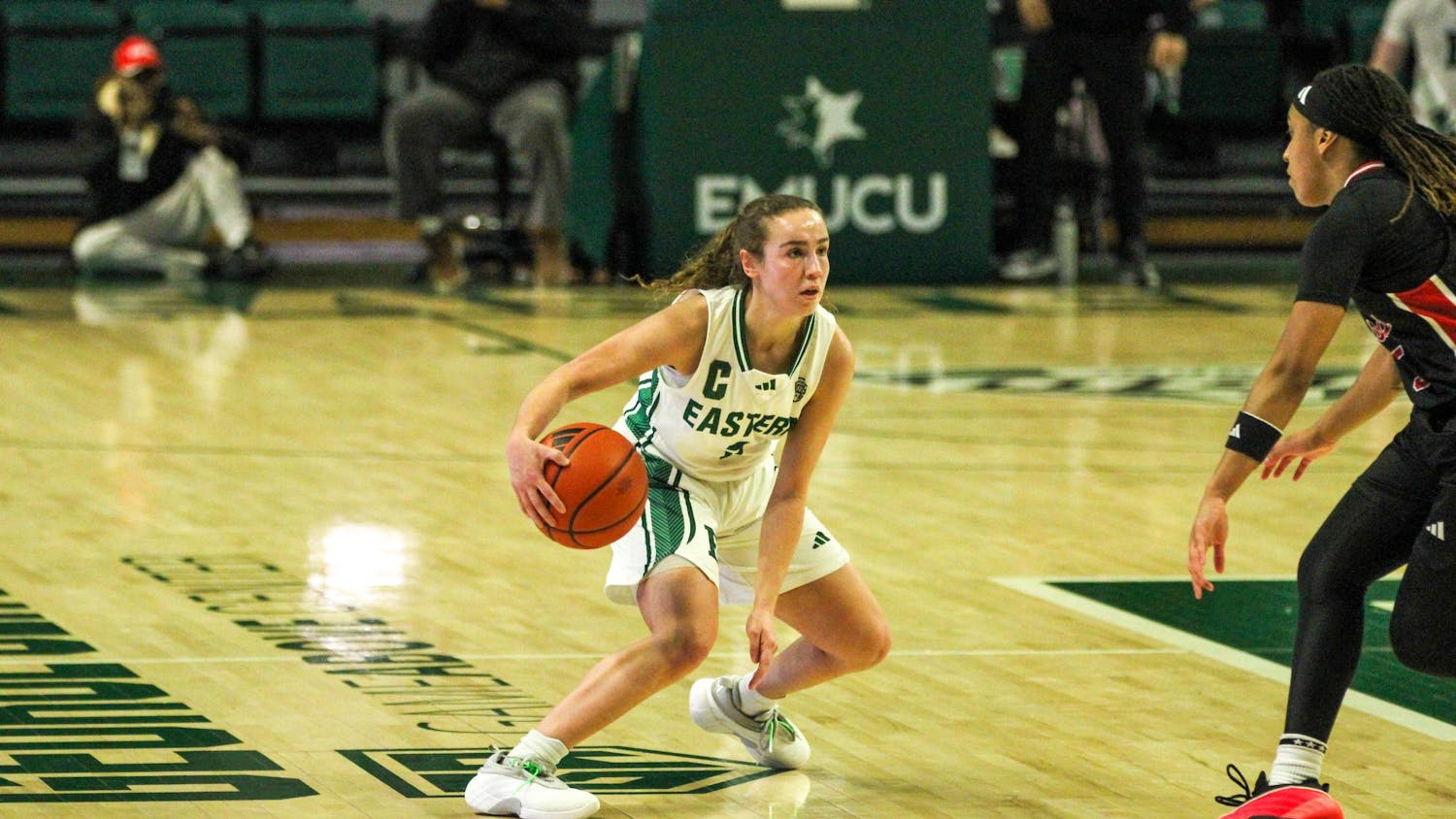 EMU player #7, in a white jersey, dribbling the basketball.