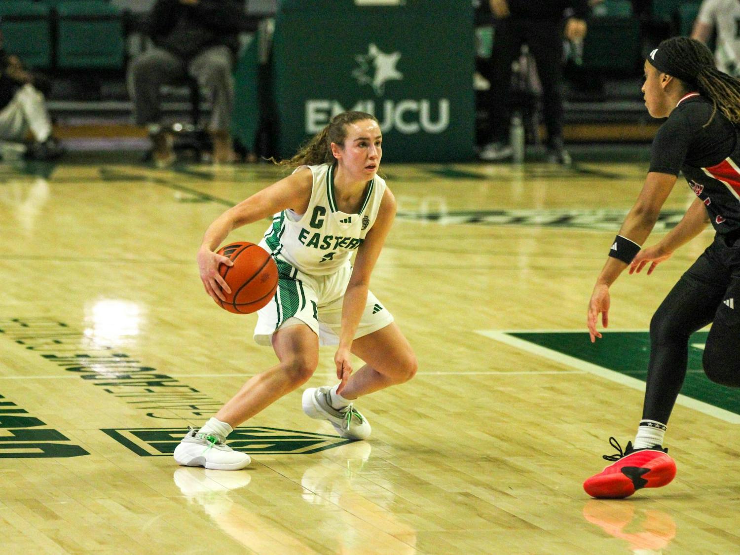 EMU player #7, in a white jersey, dribbling the basketball.