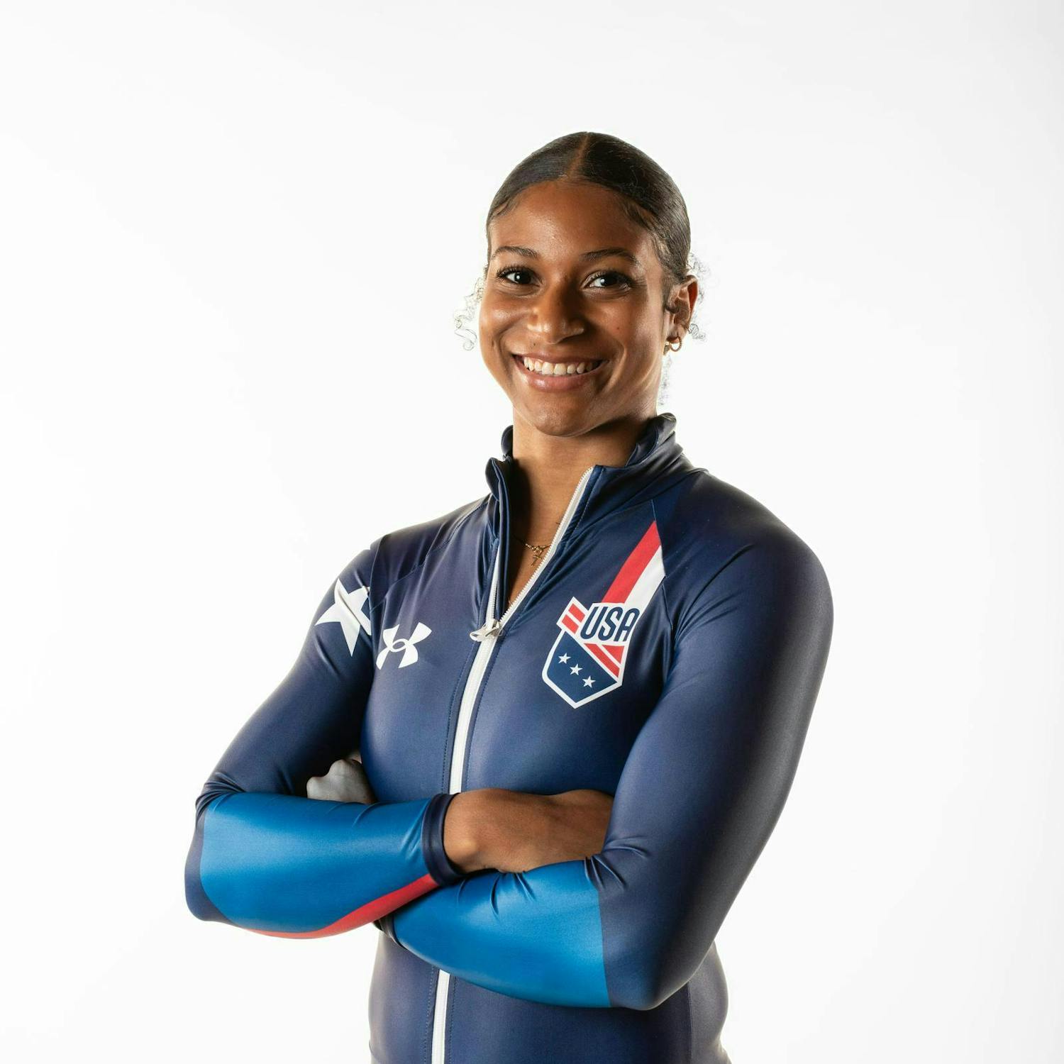Jasmine Jones wears an Olympic uniform and smiles with arms crossed.