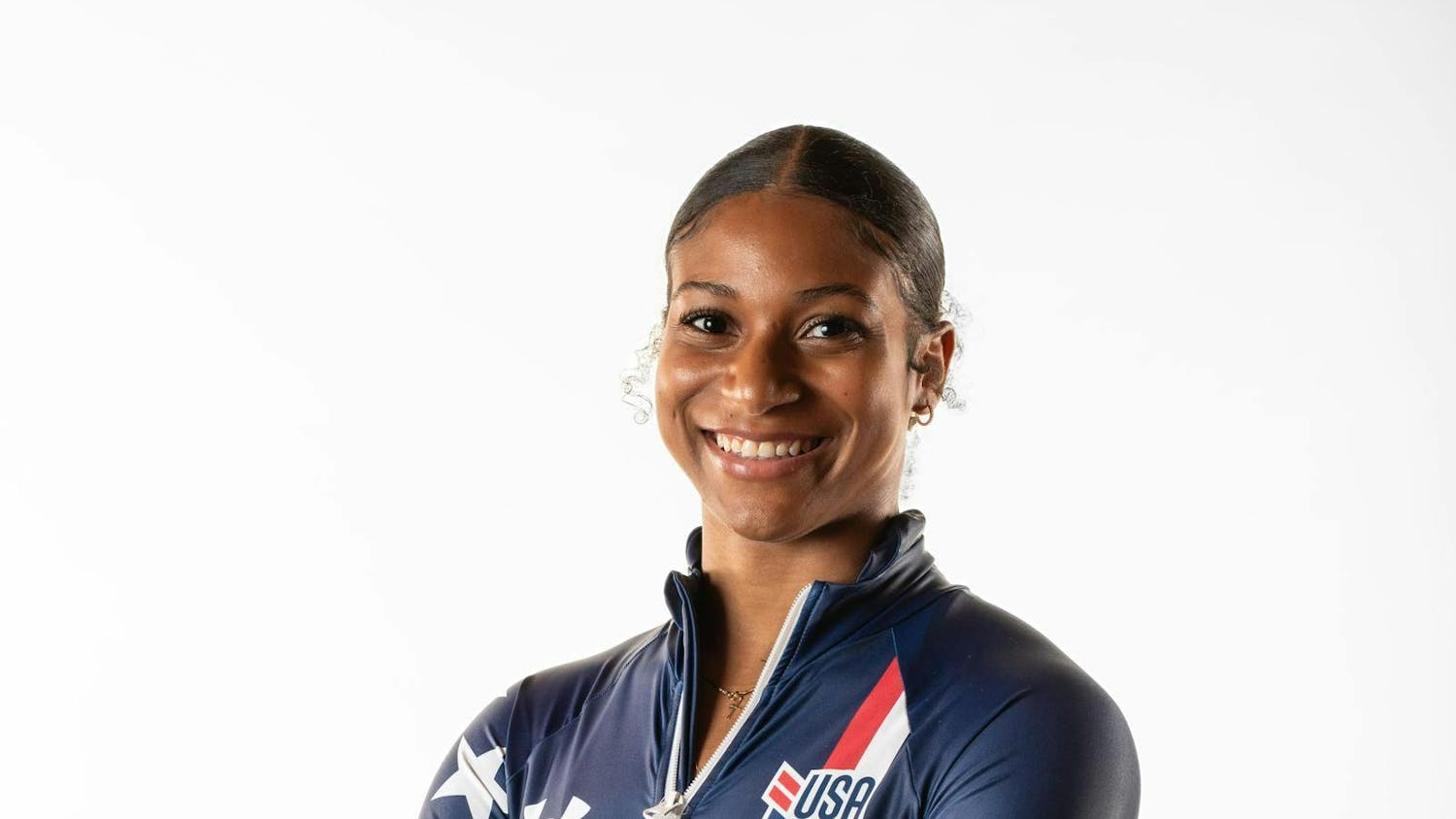 Jasmine Jones wears an Olympic uniform and smiles with arms crossed.
