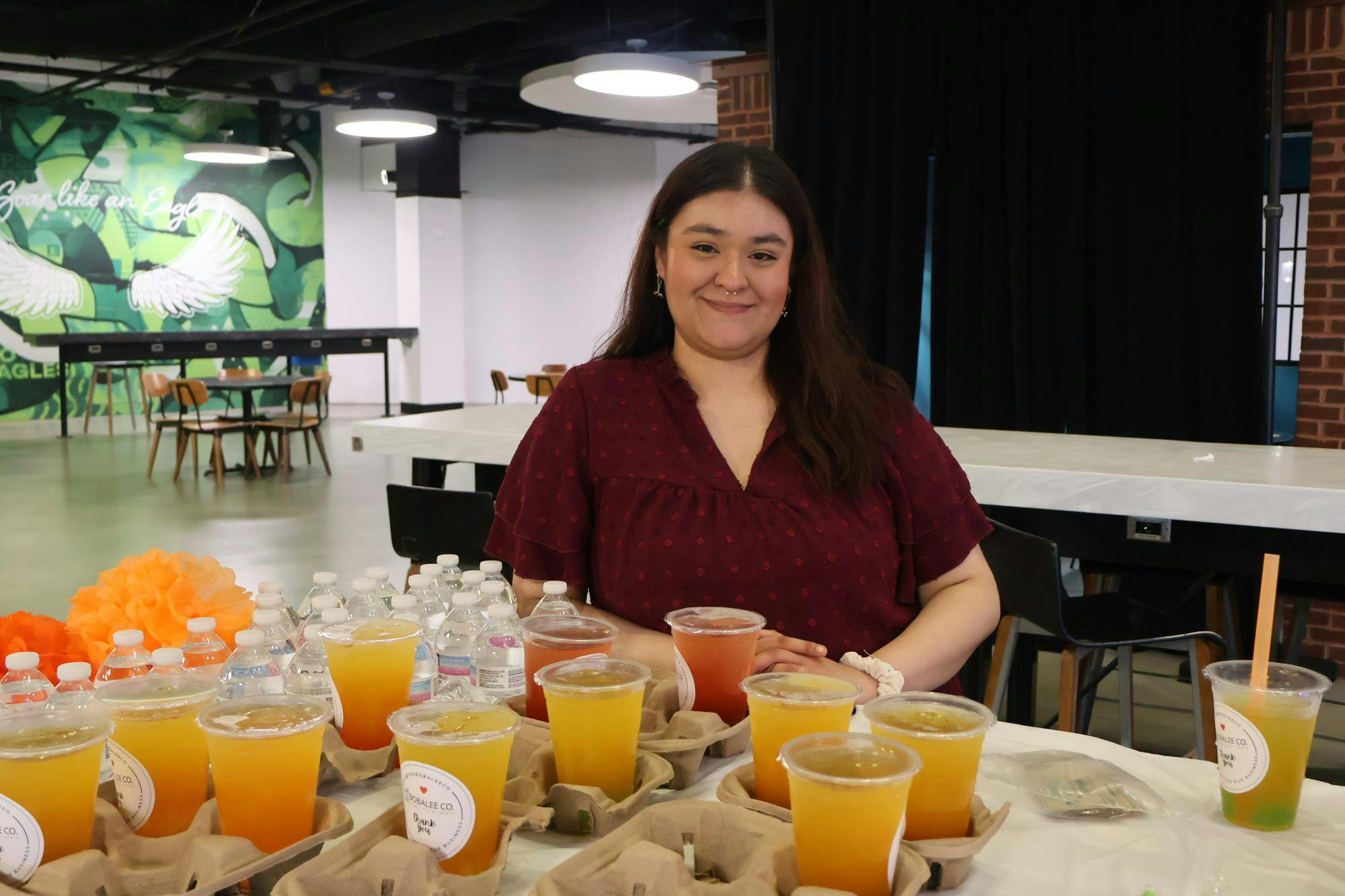 Woman standing behind table of orange bubble tea.