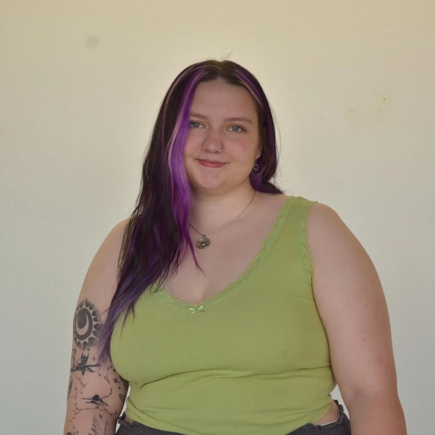 Chrissy Kuiper from the waist up, smiling in front of a blank wall at the camera.