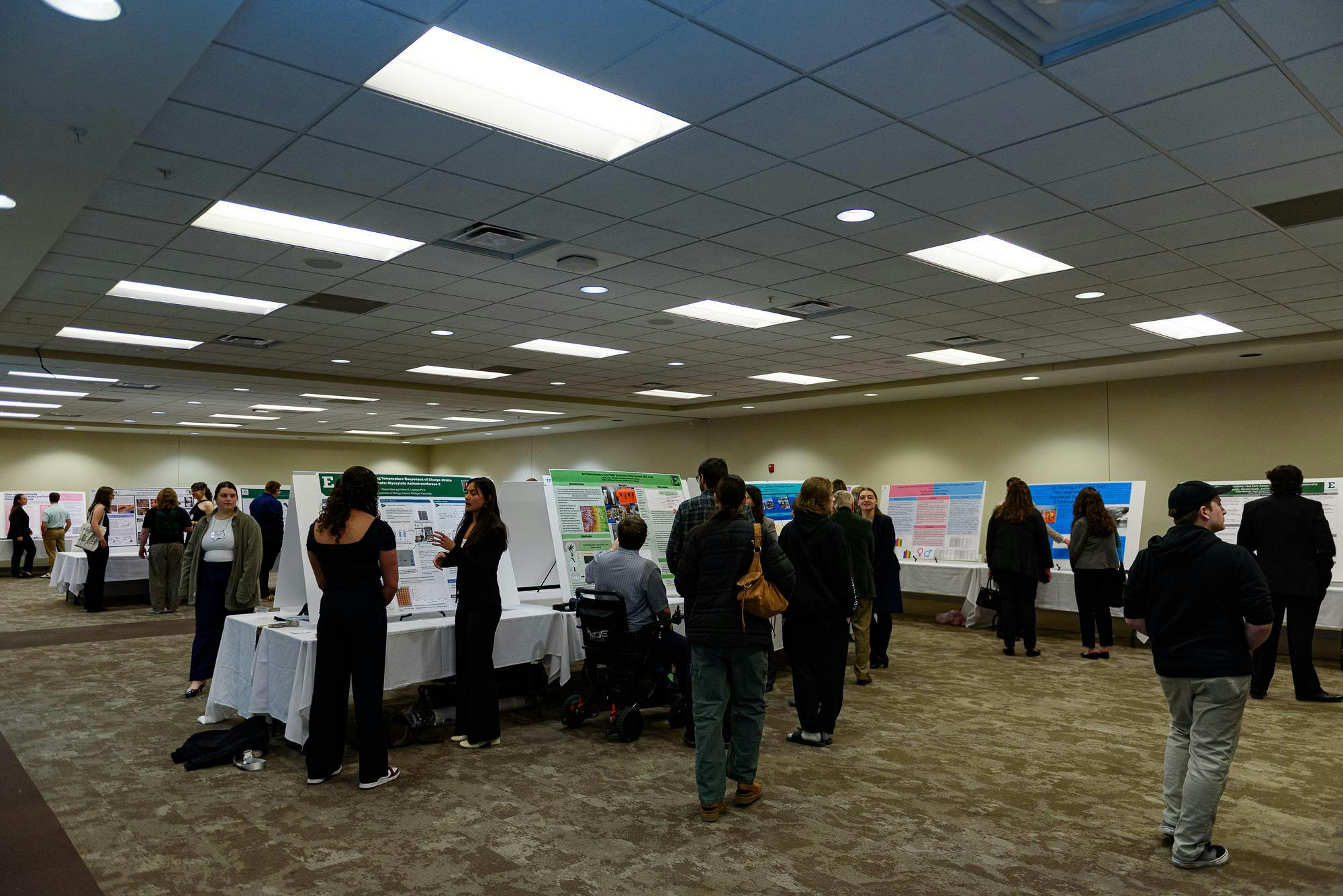 An interior room with many posters and speakers standing near said posters.