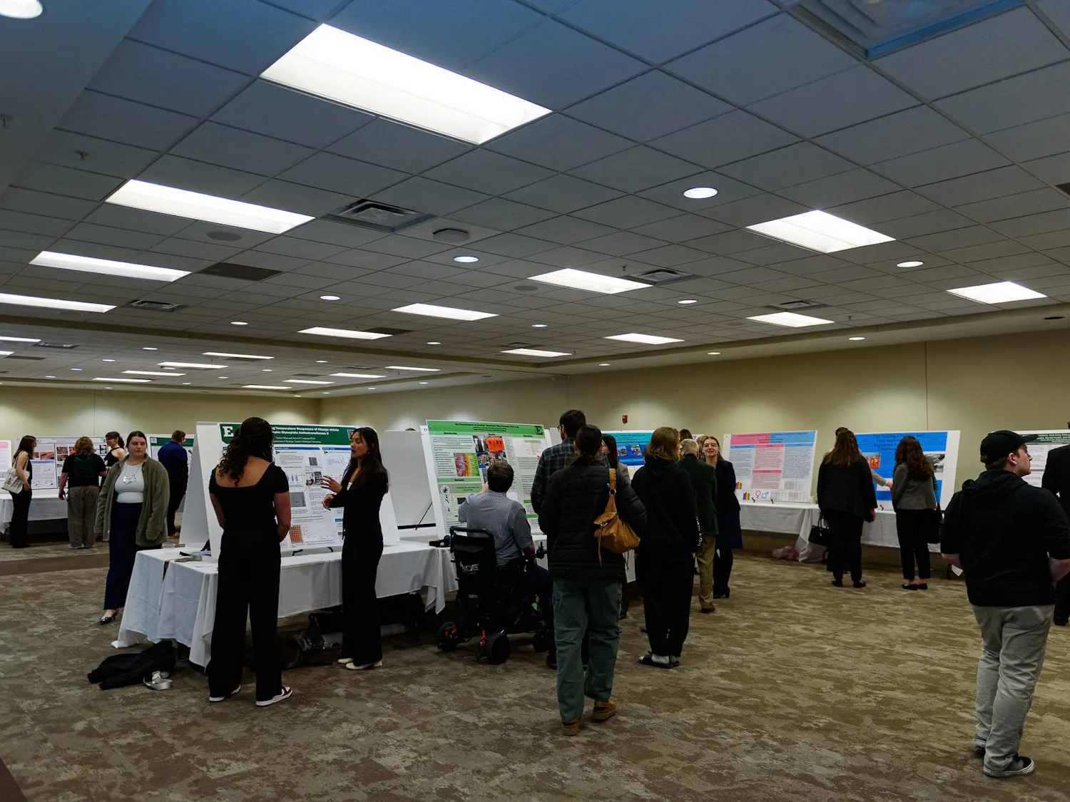 An interior room with many posters and speakers standing near said posters.