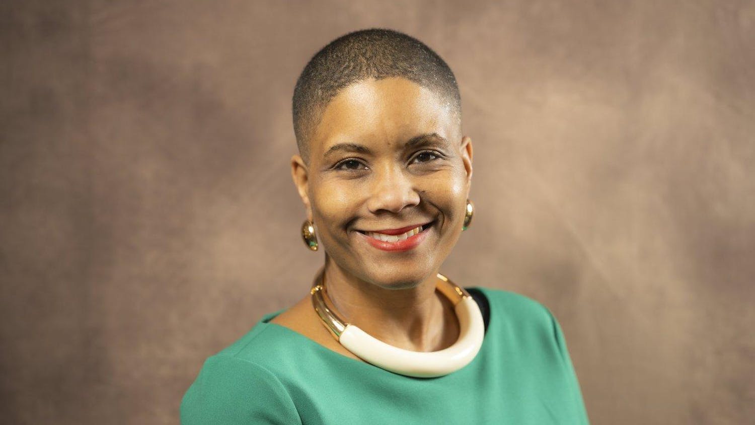 Headshot of Renee' T. Watson from the shoulders up, smiling and wearing a green blouse and gold jewelry.