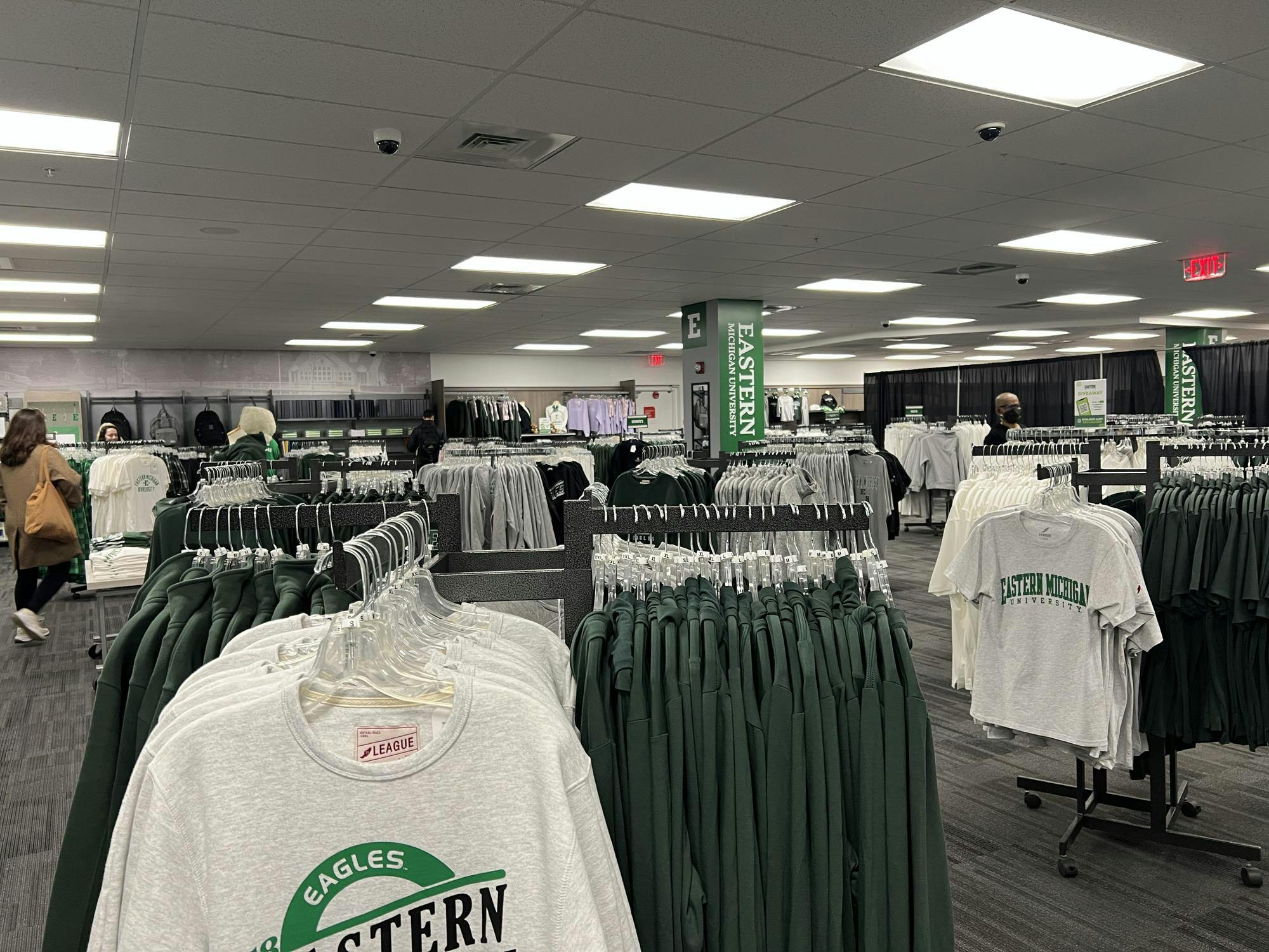 Image showing racks of gray, white and green apparel branded with Eastern Michigan University logos in a store.