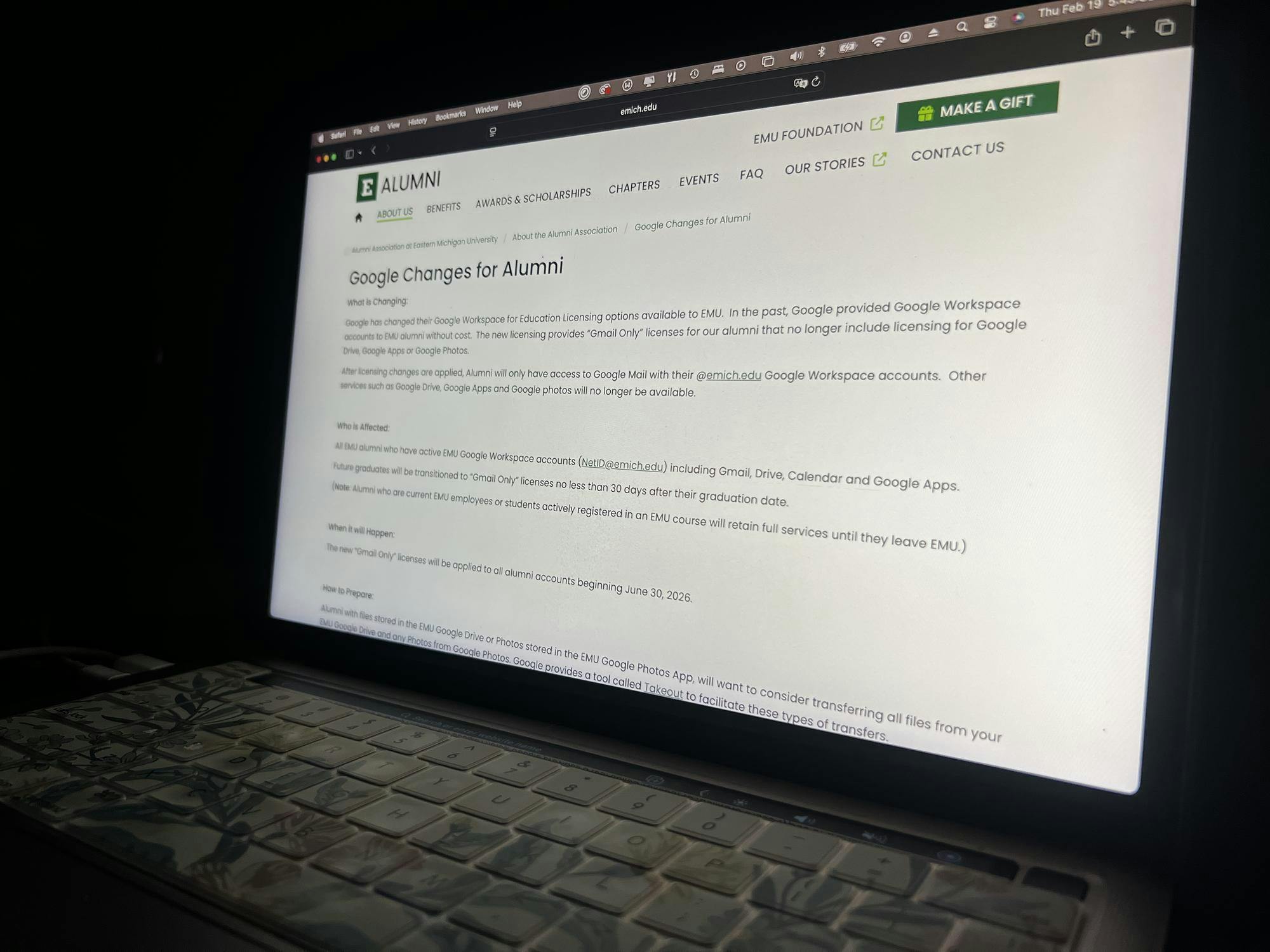 The Eastern Michigan University website glows on a computer monitor. The "Google Changes for Alumni" page is visible.