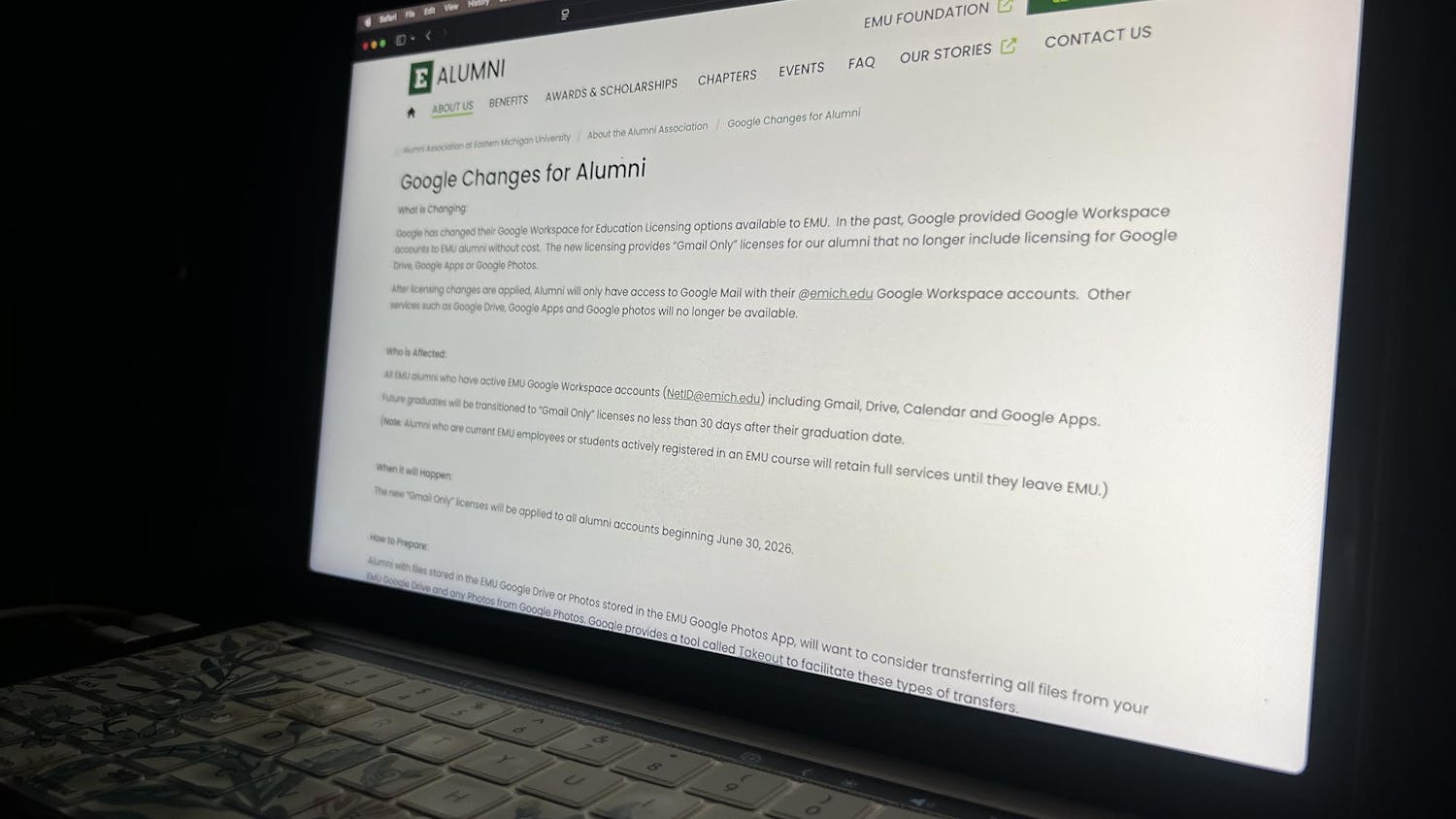 The Eastern Michigan University website glows on a computer monitor. The "Google Changes for Alumni" page is visible.