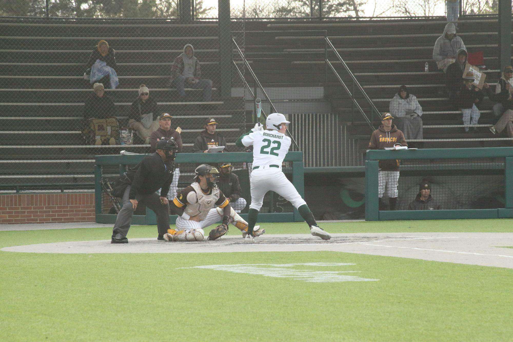 Baseball player prepares for pitch from opposing team while catcher and umpire stand positioned off to the side.
